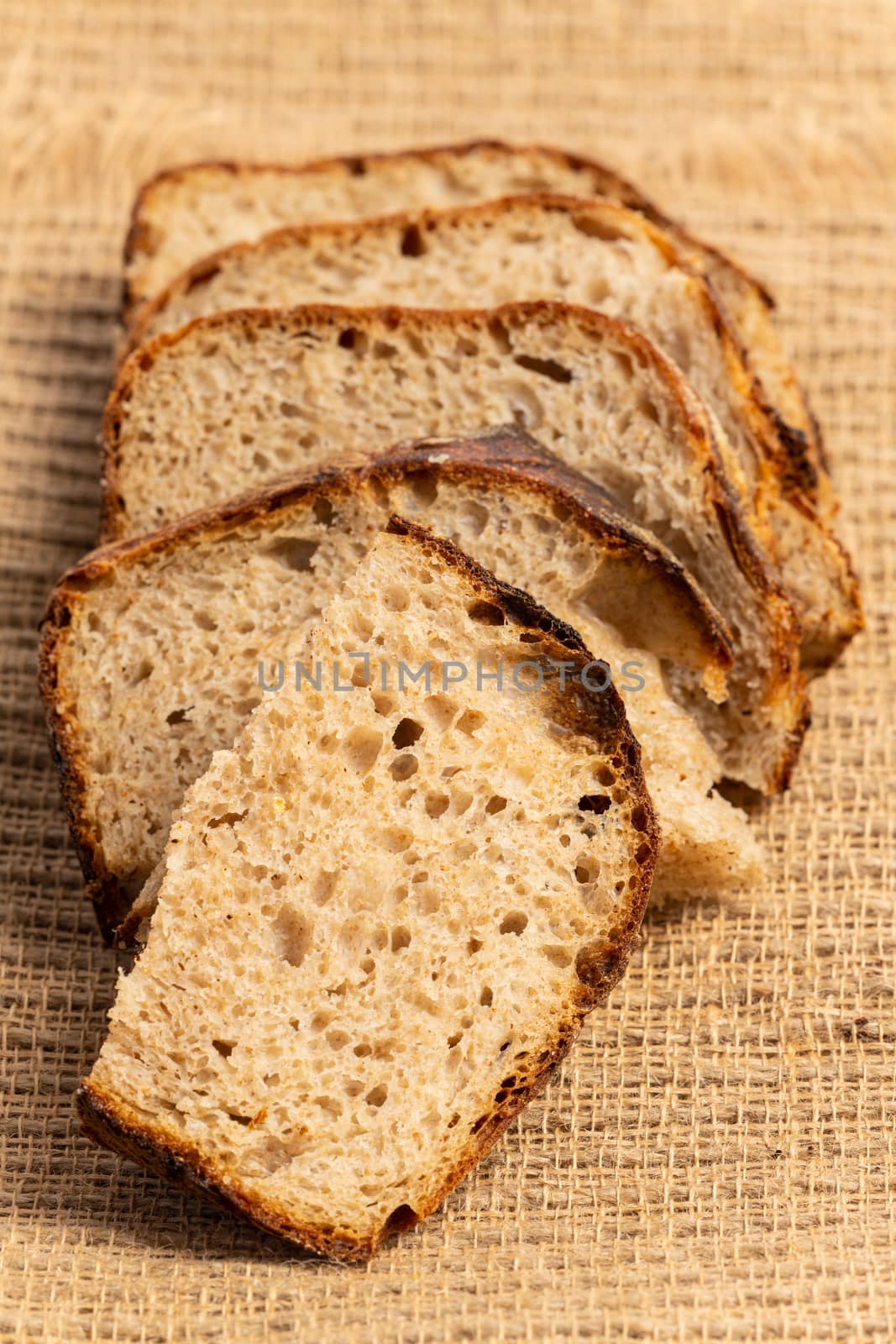 Close up of hearty artisan sourdough bread slices on jute fabric.