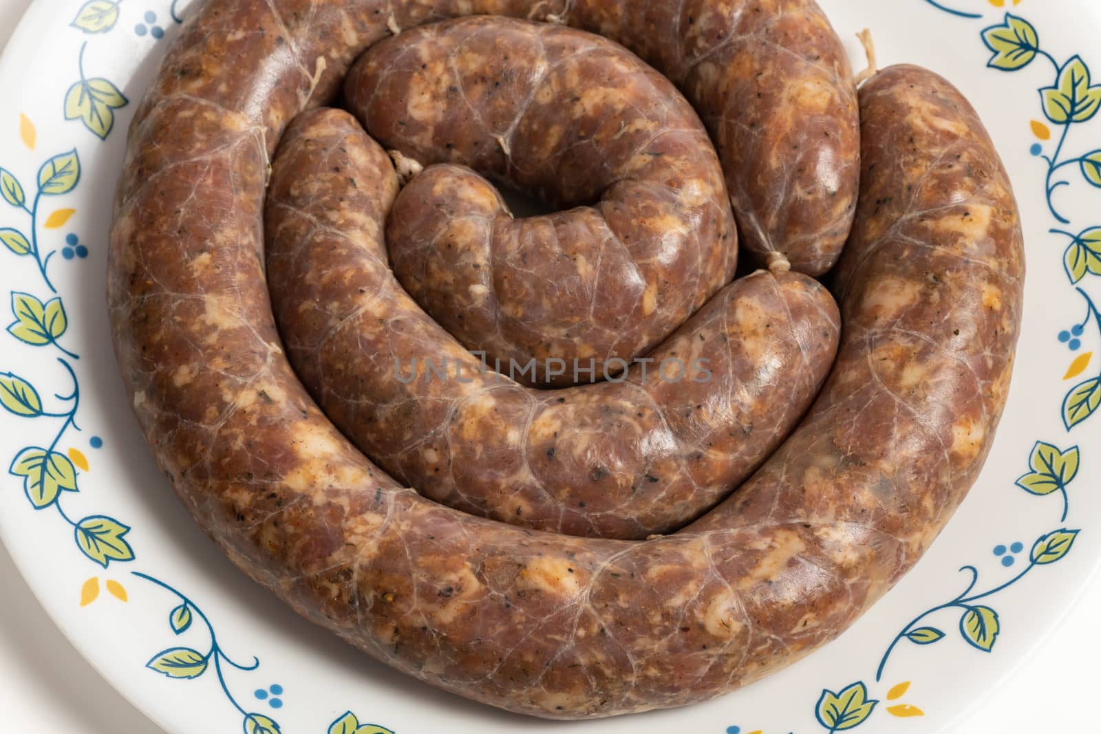 Homemade stuffed pork sausages in a a plate isolated on white.