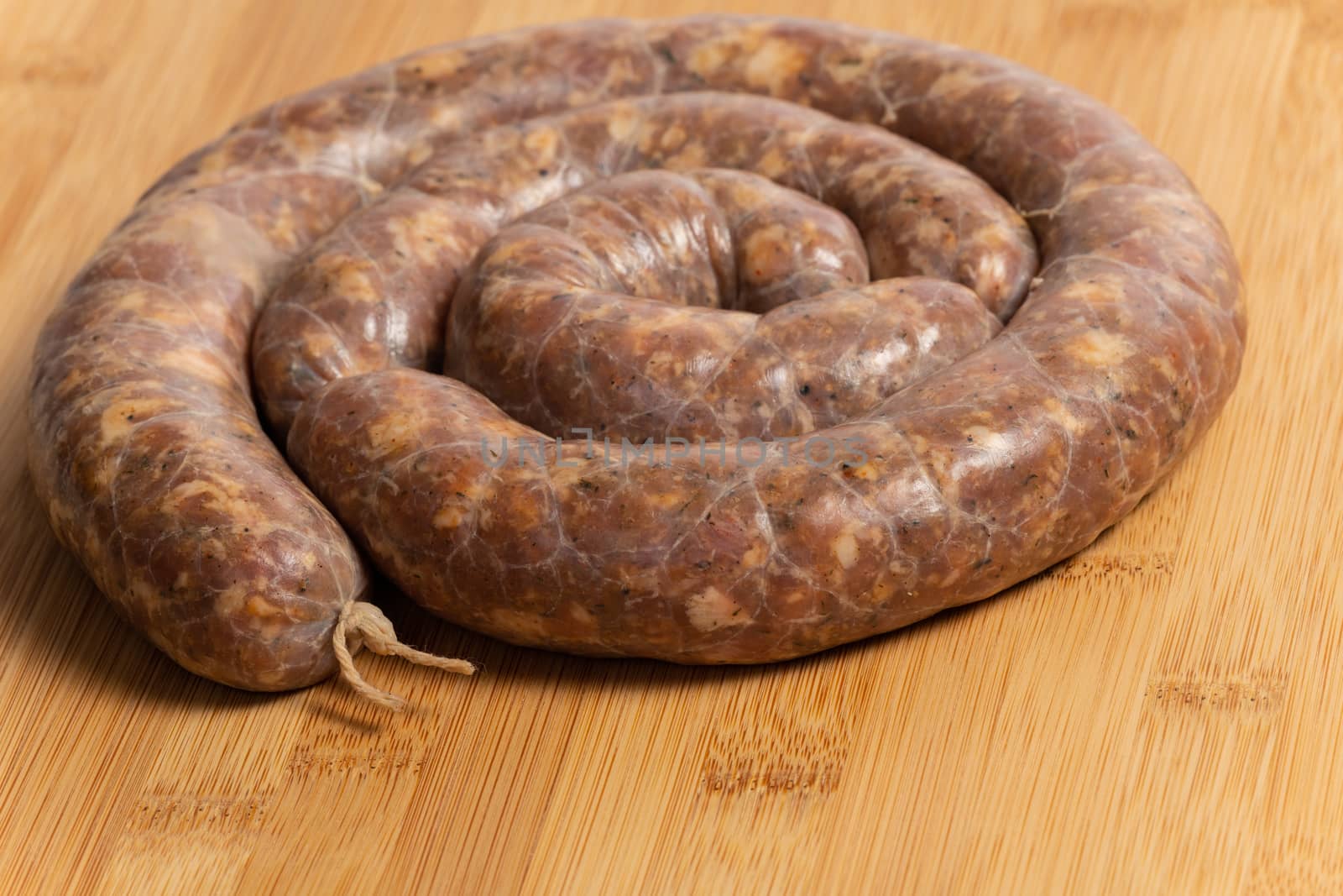 Raw homemade stuffed pork sausages isolated on a woodboard.