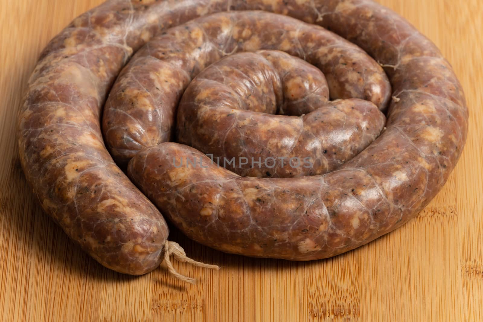 Raw homemade stuffed pork sausages isolated on a woodboard.