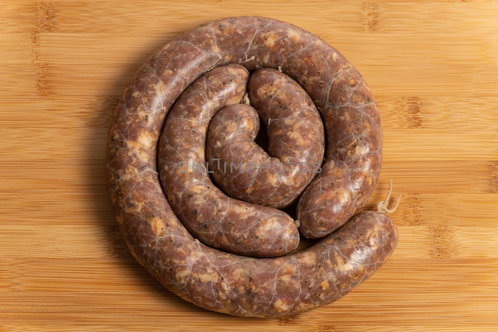 Raw homemade stuffed pork sausages isolated on a woodboard.