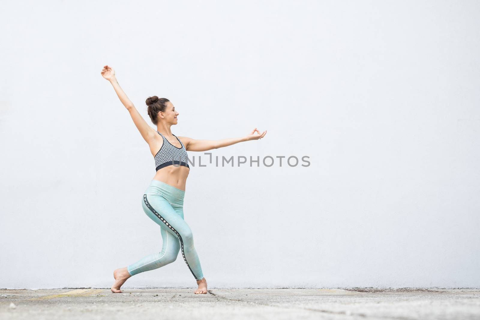Fit sporty active girl in fashion sportswear doing yoga fitness exercise in front of gray wall, outdoor sports, urban style.