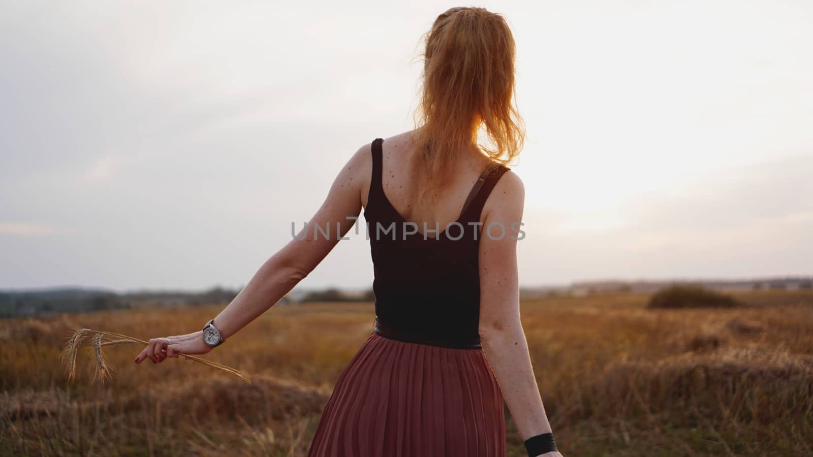 Happy young woman enjoying nature and sunlight in straw field