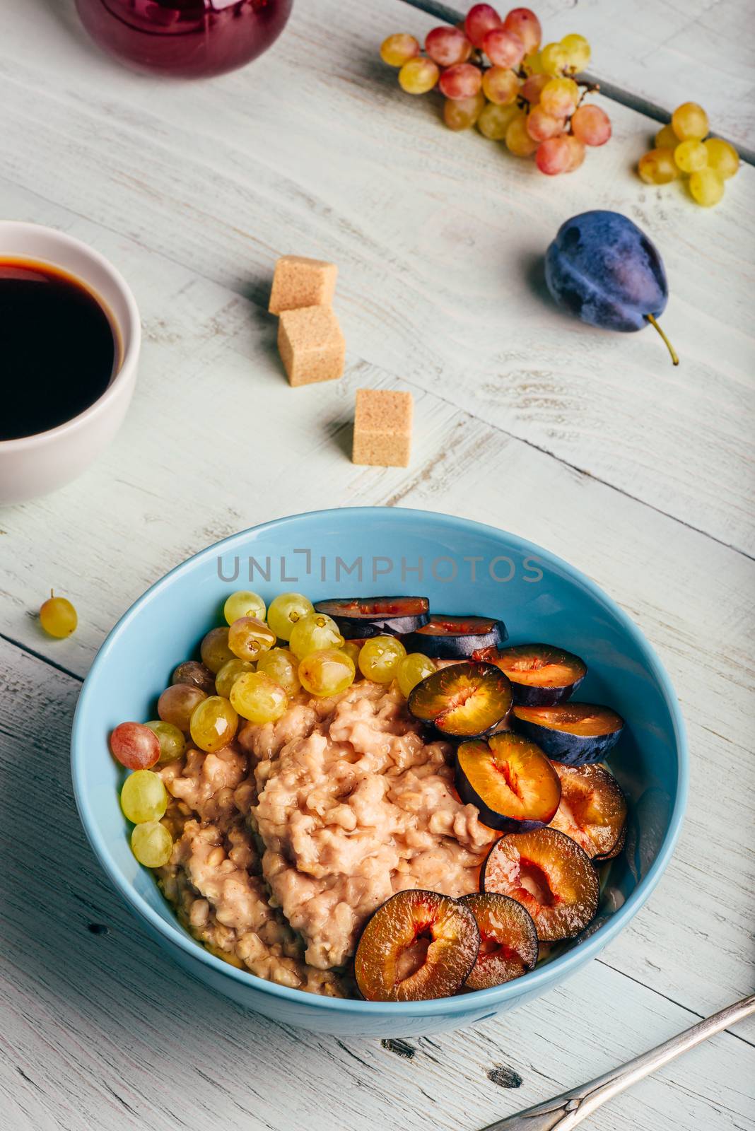 Porridge with fresh plum, green grapes and cup of coffee. by Seva_blsv