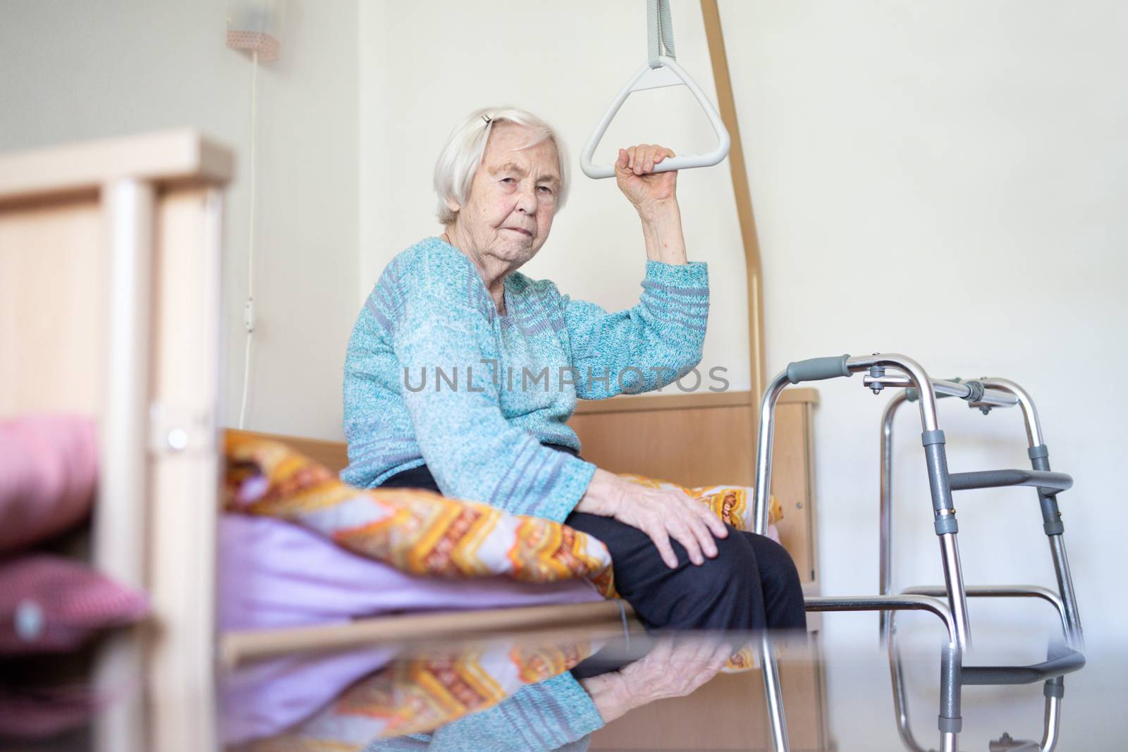Elderly 96 years old woman sitting on medical bed in hospic. Palliative health care support for older people concept. Care for the elderly.