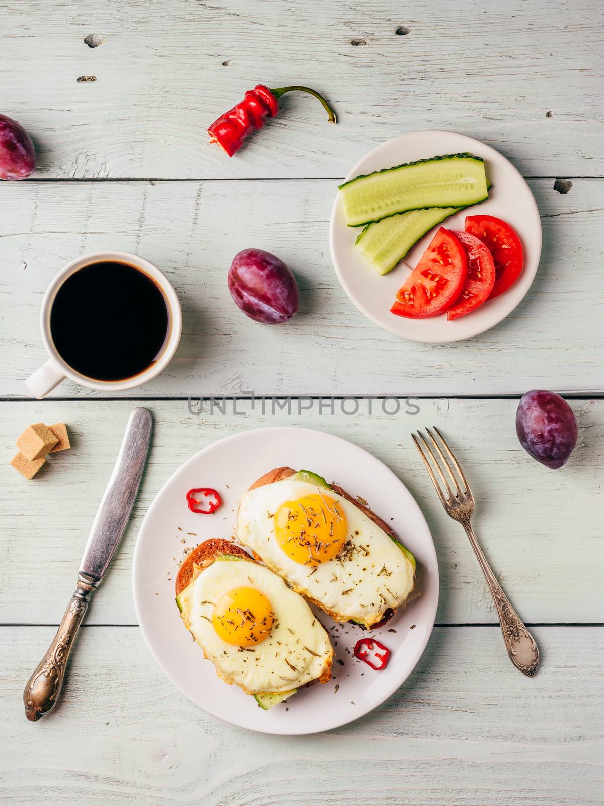 Breakfast toasts with vegetables and fried egg on white plate, cup of coffee and some fruits over wooden background. Dieting food concept. View from above.
