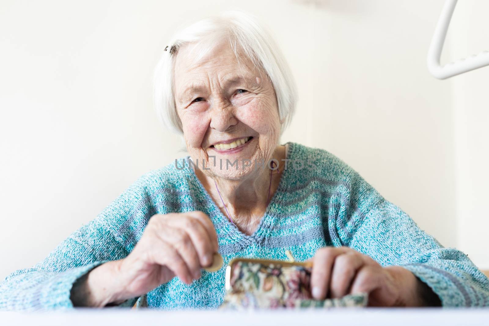 Cheerful elderly 96 years old woman sitting at table at home happy with her pension savings in her wallet after paying bills. Saving for retirement and financial planing concept.