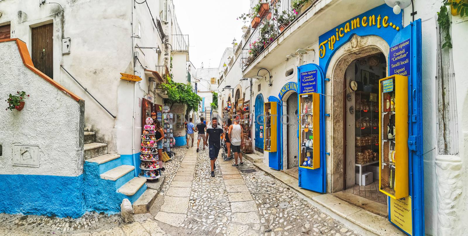 Peschici, Italy, 10 July 2019 - panoramic shot of mediterranean town tourists stores and people