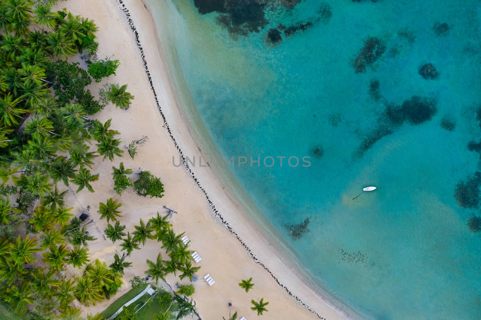 Aerial view of tropical beach with white boat anchored.Samana peninsula,Bahia Principe beach,Dominican Republic.