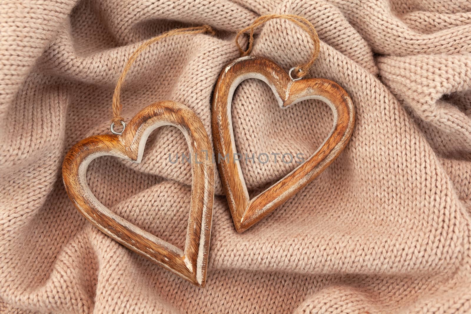 Cozy autumn winter composition. Layout of wooden hearts on a warm sweater. Scandinavian style, hygge. Horizontal flat lay. Daylight.