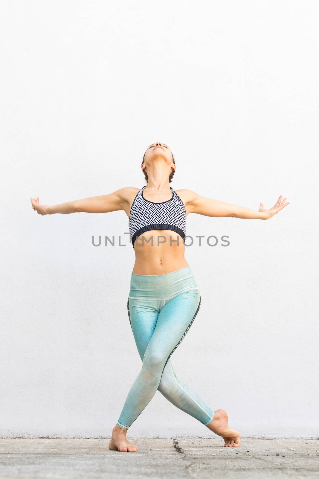 Fit sporty active girl in fashion sportswear doing yoga fitness exercise in front of gray wall, outdoor sports, urban style.
