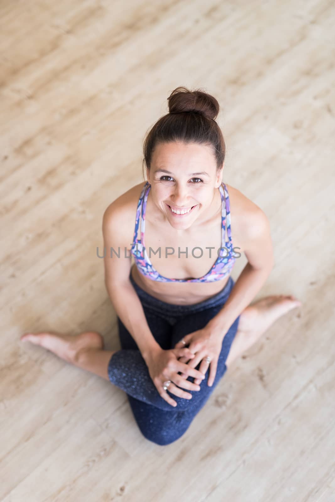 Cheerful fit sporty active girl in fashion sportswear sitting on the floor in yoga studio. Active urban lifestyle.