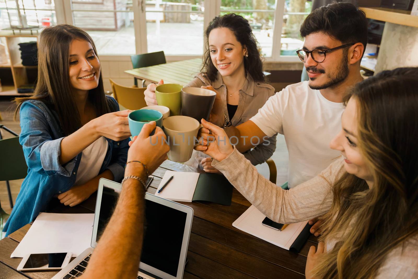 Group of friends studying together and making a toast with coffee