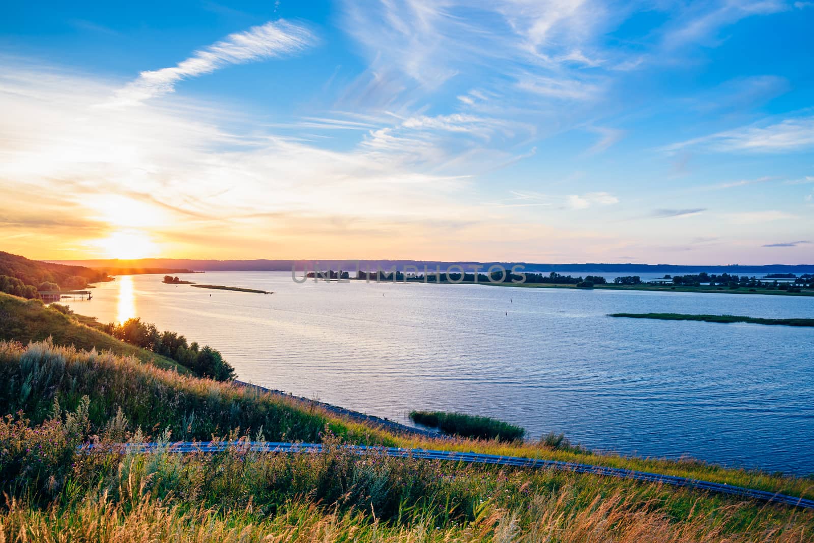 River shore in the sunset light. Blue cloudy sky.