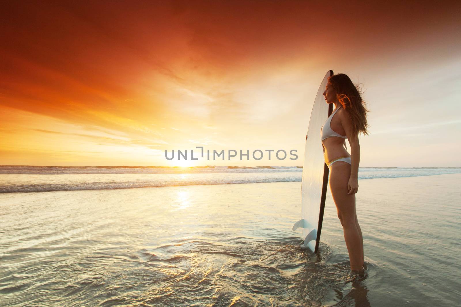 Surfer woman on beach at sunset by Yellowj