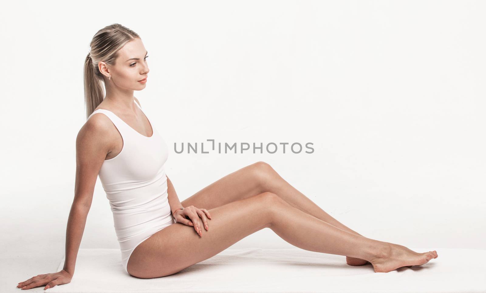 Young beautiful woman in white cotton underwear sitting isolated on white background