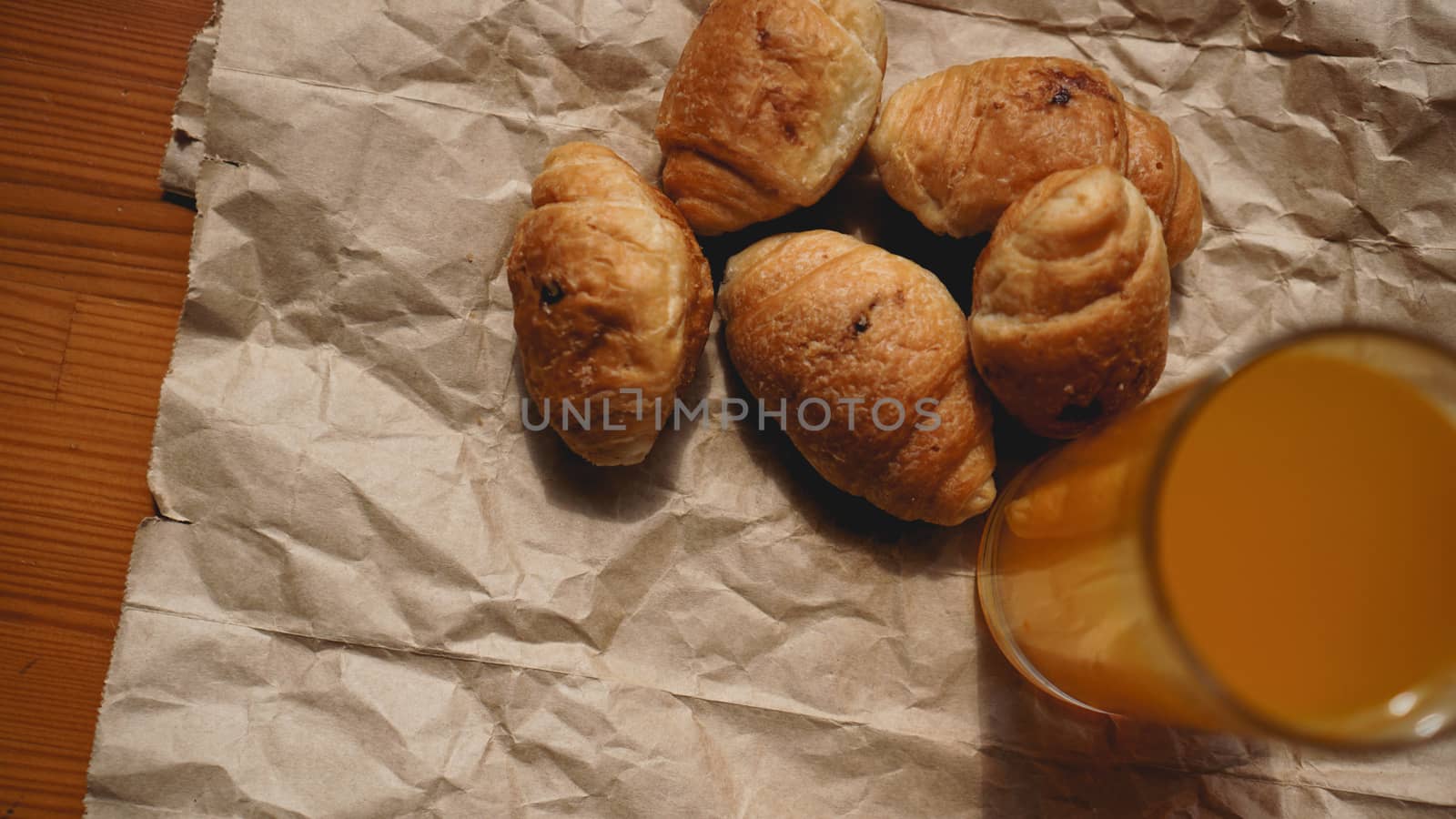 Freshly baked croissants with orange juice on kraft paper. Delicious dessert by natali_brill
