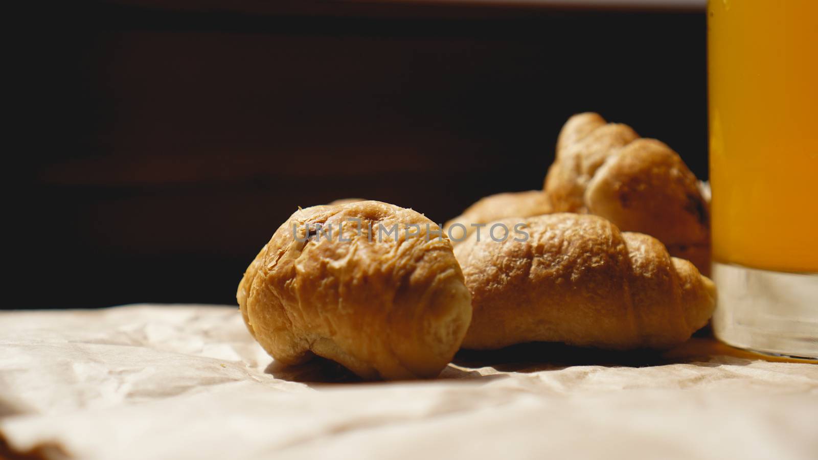 Freshly baked croissants with orange juice on kraft paper. Closeup photography of fresh delicious dessert for breakfast.