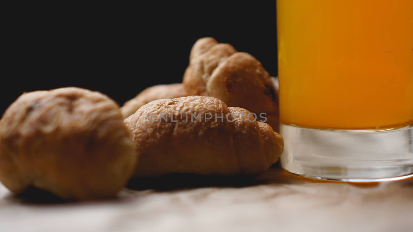 Freshly baked croissants with orange juice on kraft paper. Delicious dessert by natali_brill