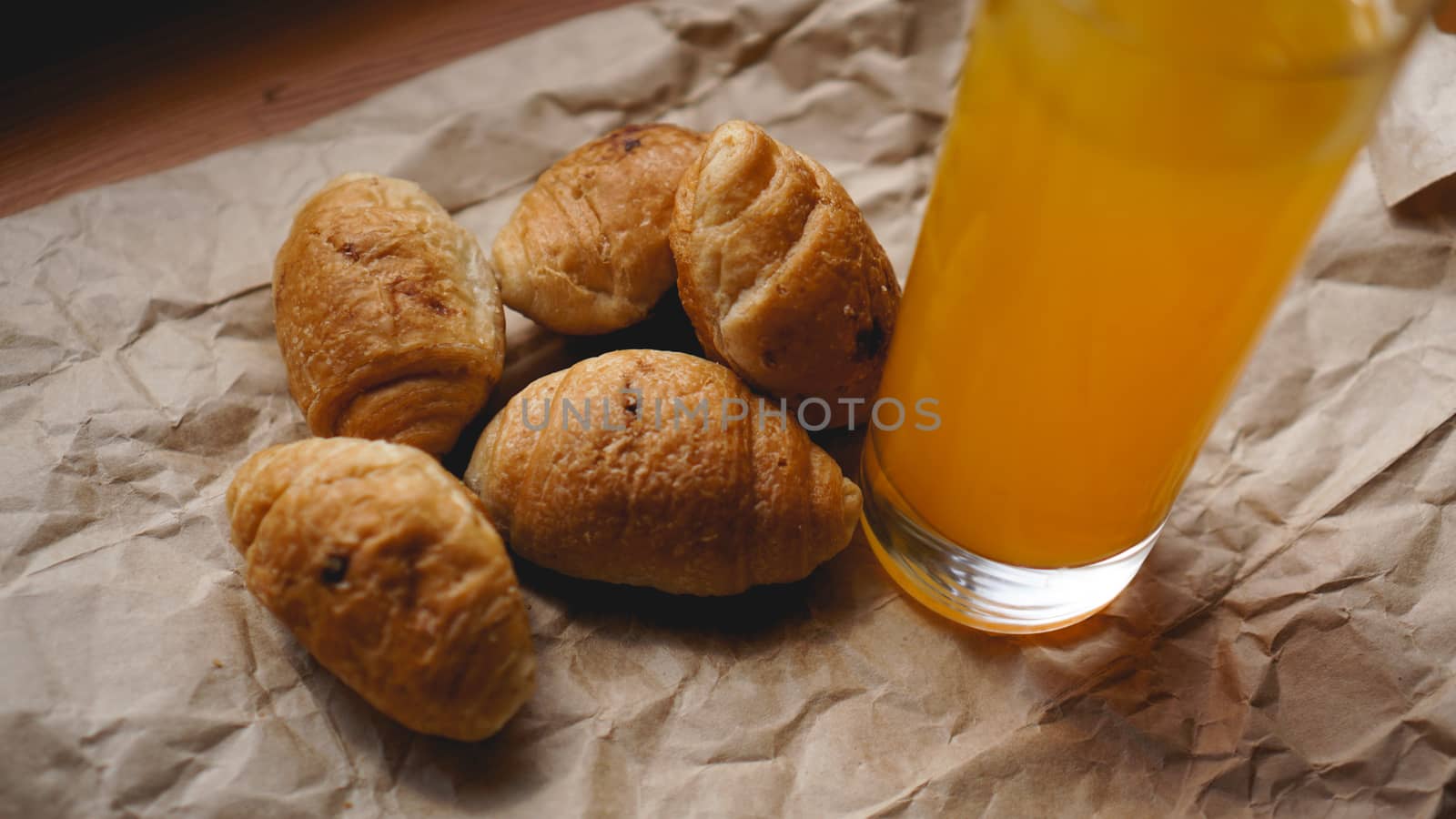 Freshly baked croissants with orange juice on kraft paper. Delicious dessert by natali_brill