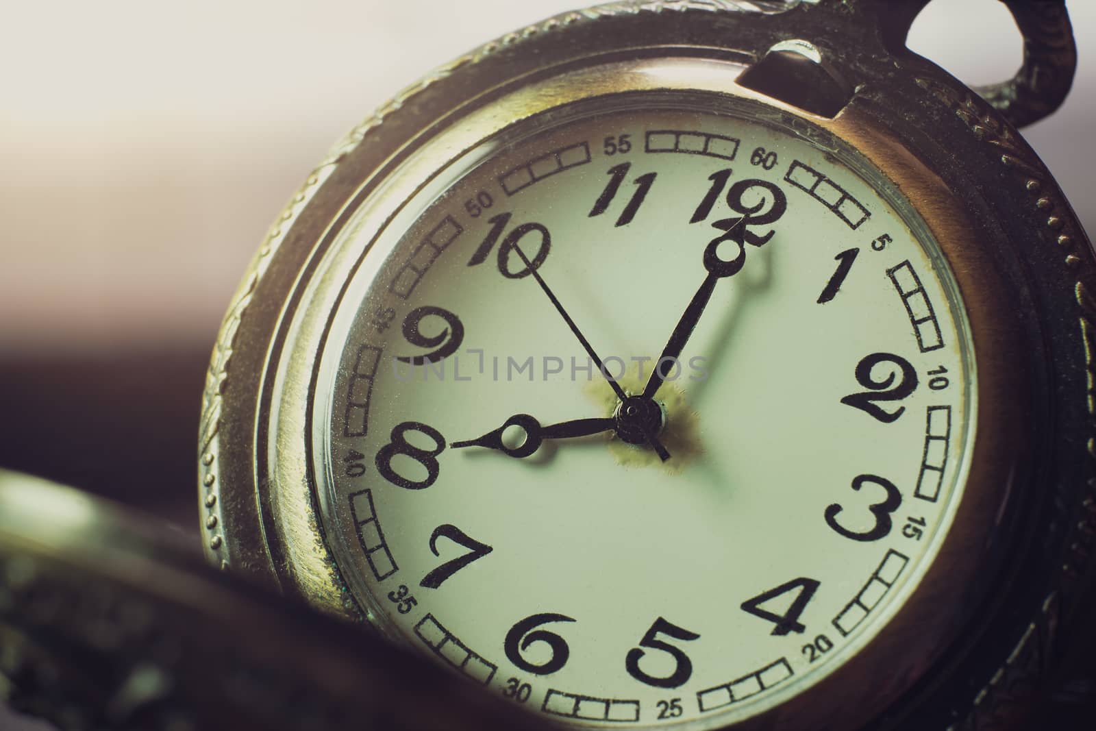 Closeup pocket watch on table and sunlight. At 8 am. o'clock in the morning. Concept of starting work today.