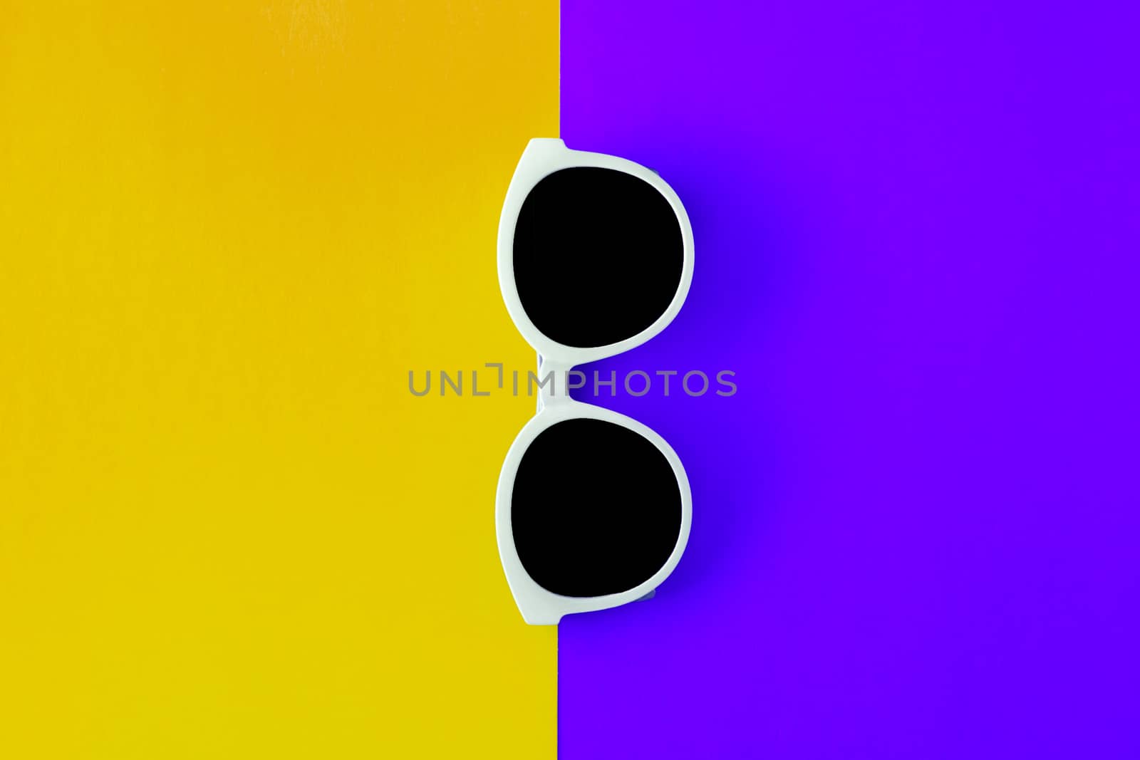 Sunny stylish white sunglasses on a bright purple-lilac and yellow-orange background, top view, isolated. Copy space. Flat lay by Tanacha