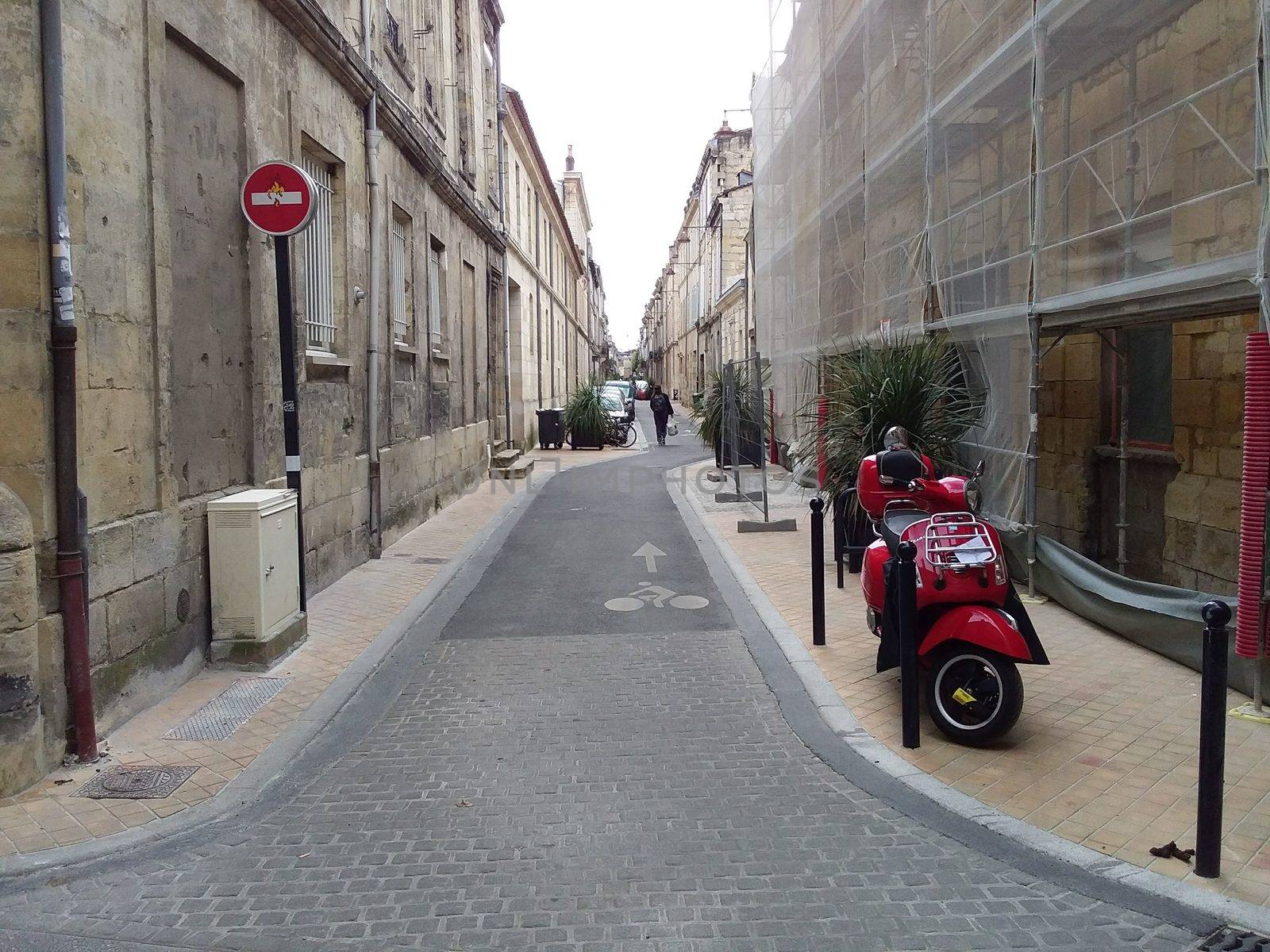 Red vintage scooter parked on sidewalk of empty city street. by natalia_voroshilova