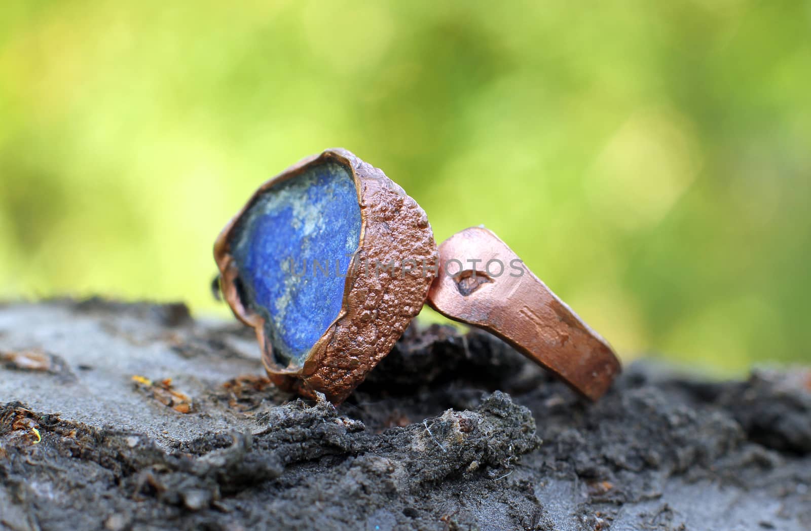 a Hand made copper ring with blue semiprecious stone on the wooden background