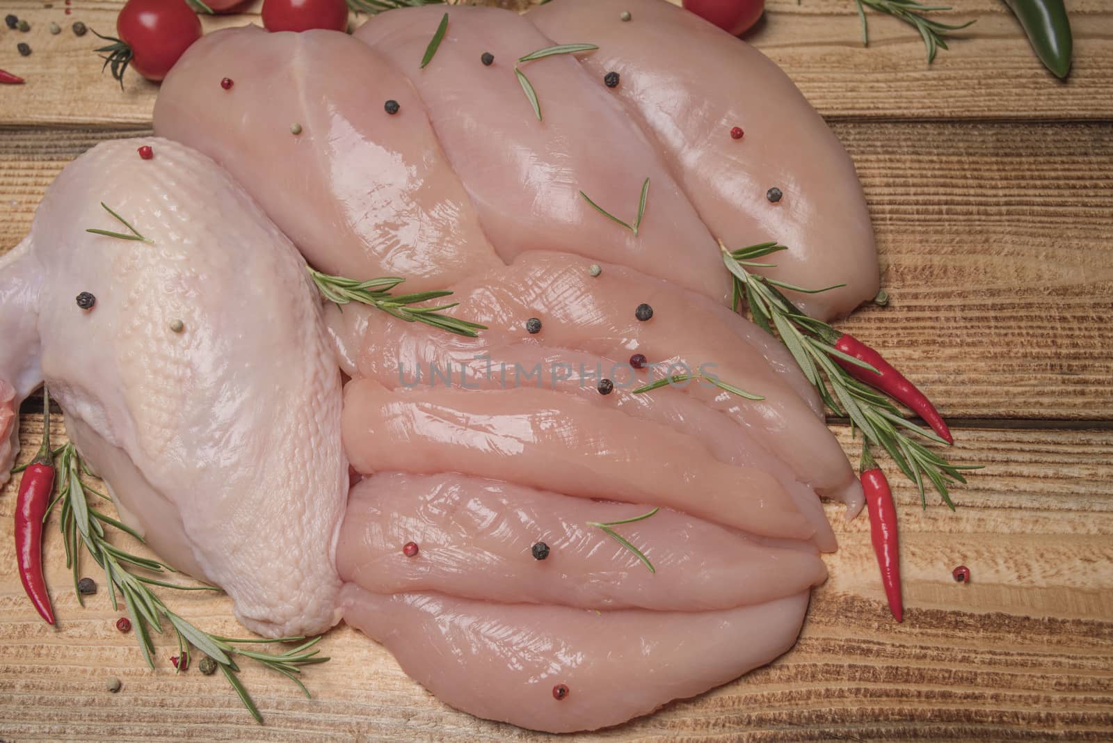 .Raw chicken meat on wooden board. Healthy eating.Raw, fresh chicken meat platter on a wooden surface with spices for cooking.