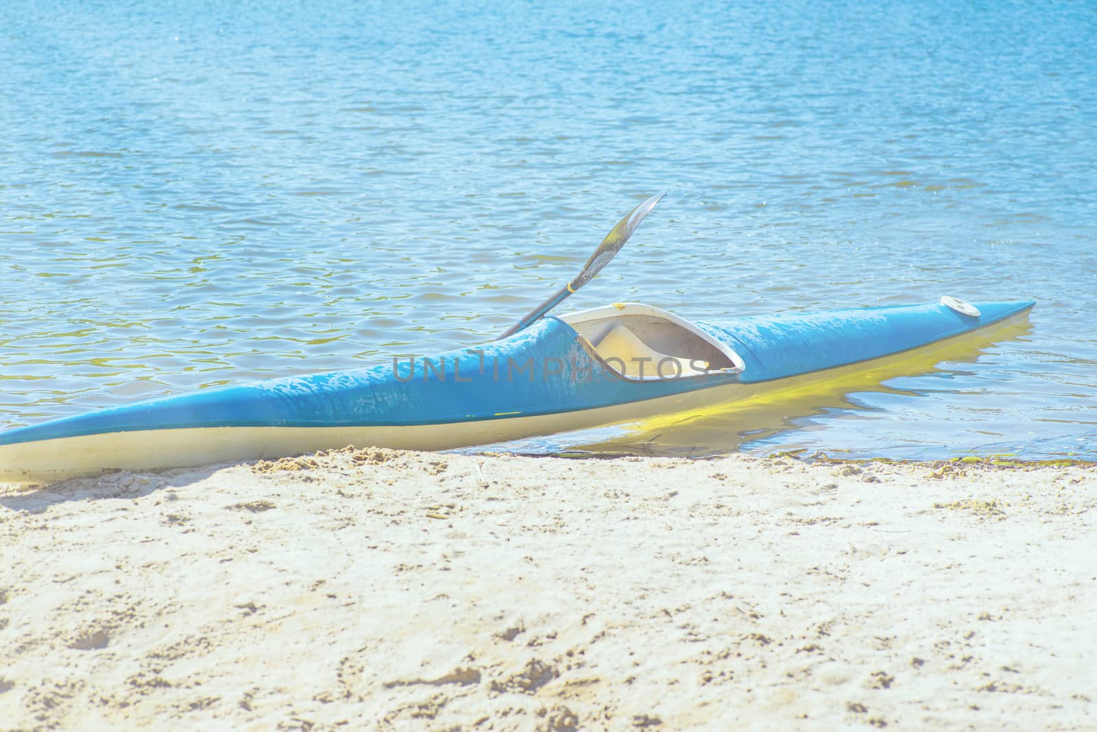 Kayak on the beach. Kayak blue and yellow. Boat on the river bank. Summer sunny day. Kayak sport.Kayaking concept.