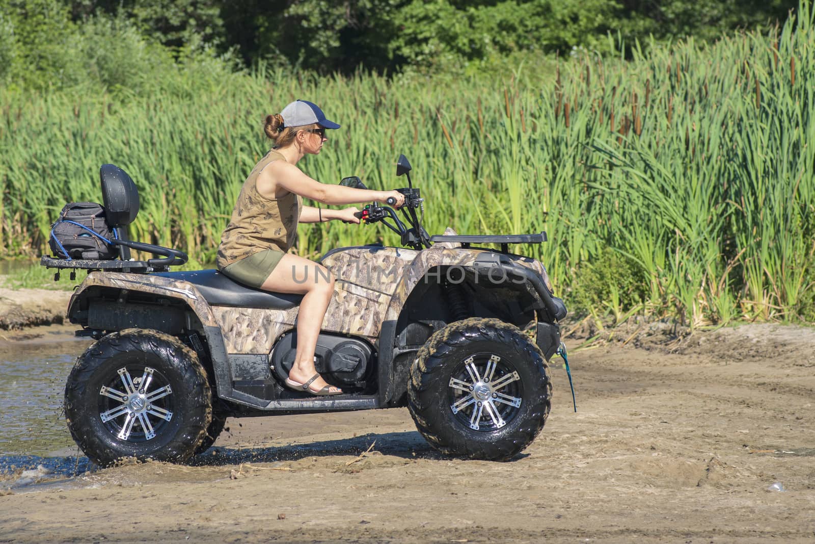 A girl on a Quad bike riding on the beach. A happy woman riding a quad bike on the river.