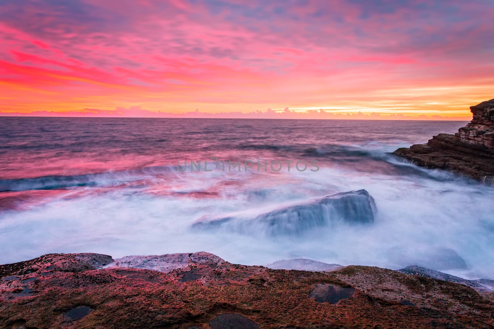 Blazing red pink orange and yellow sunrise skies over the east Sydney coastline