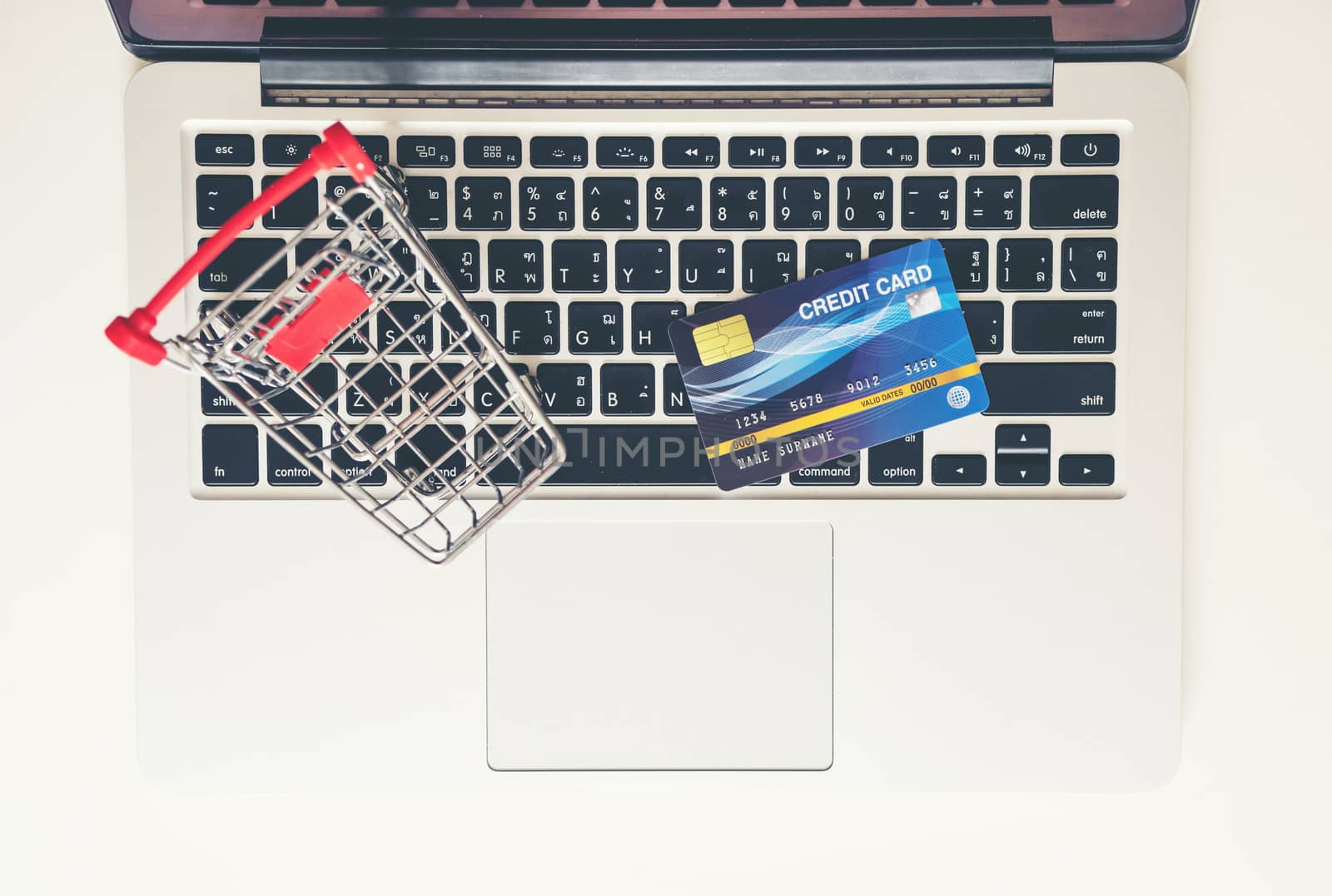 Shopping cart and credit card with laptop on the desk by anankkml