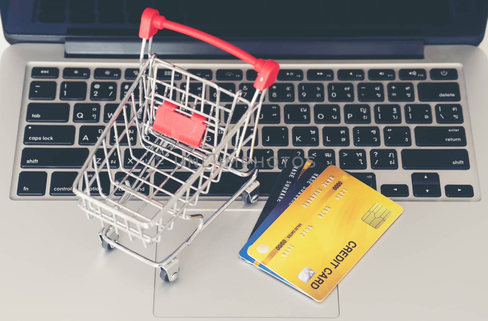 Shopping cart and credit card with laptop on the desk by anankkml