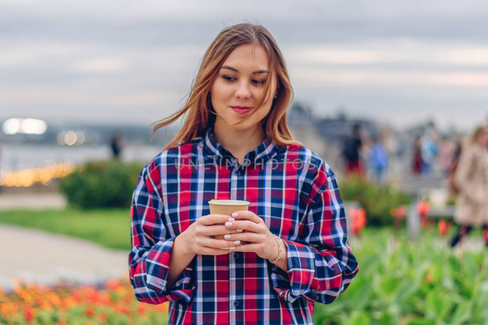 Coffee on the go. Beautiful young woman holding coffee cup and standing in the park