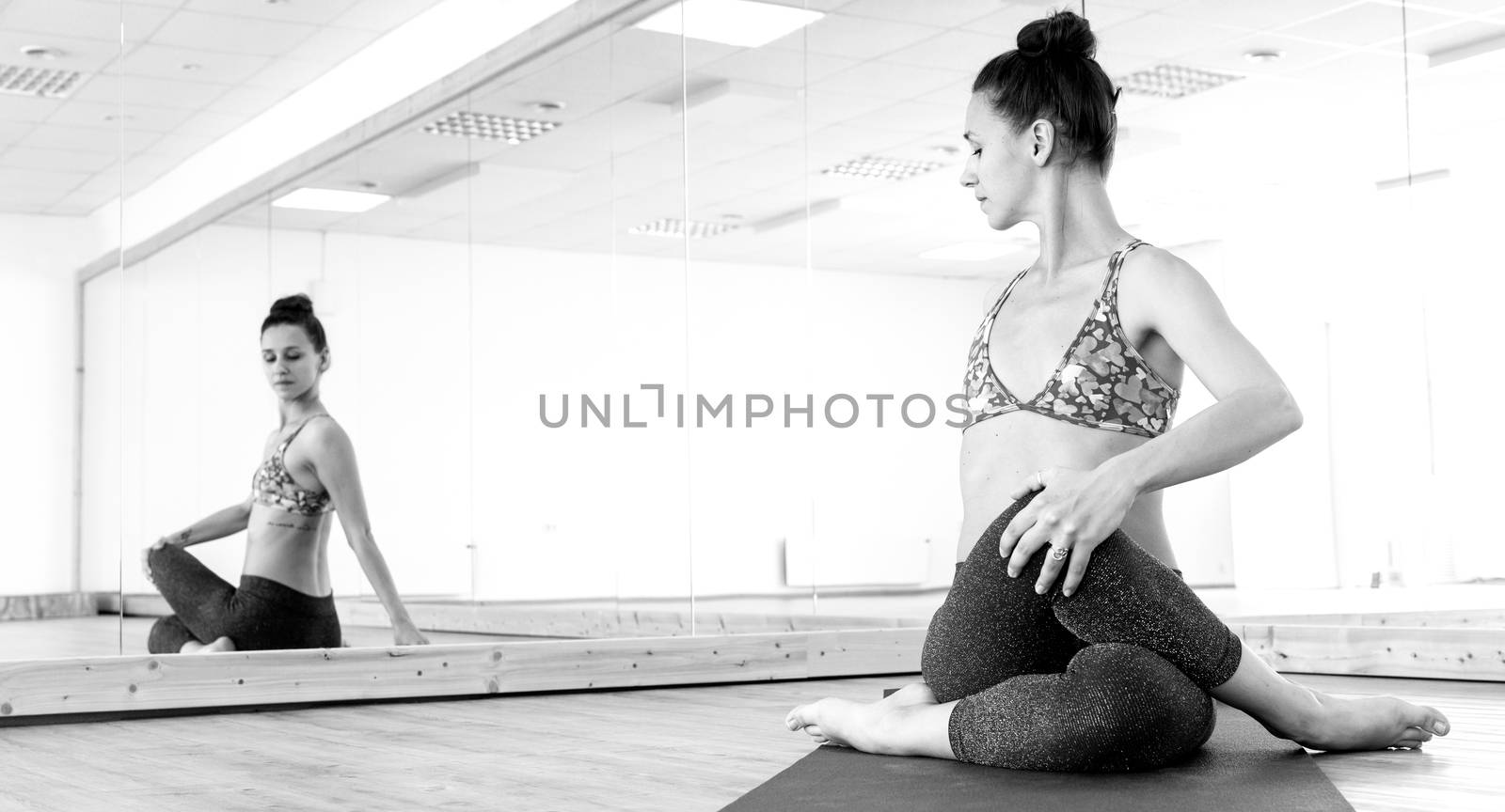 Fit sporty active girl in fashion sportswear doing yoga fitness exercise in in yoga studio. Active urban lifestyle. Black and white photo.