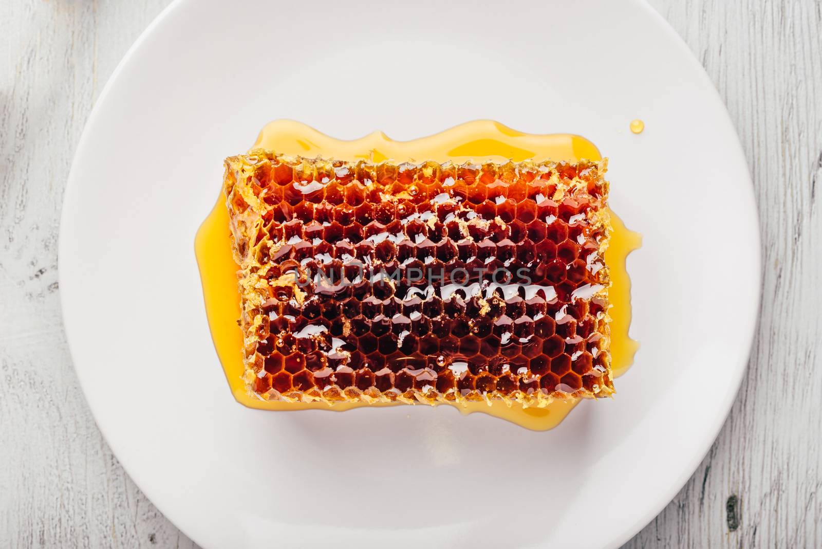 Top view of delicious yummy honeycomb on bright plate over light wooden background