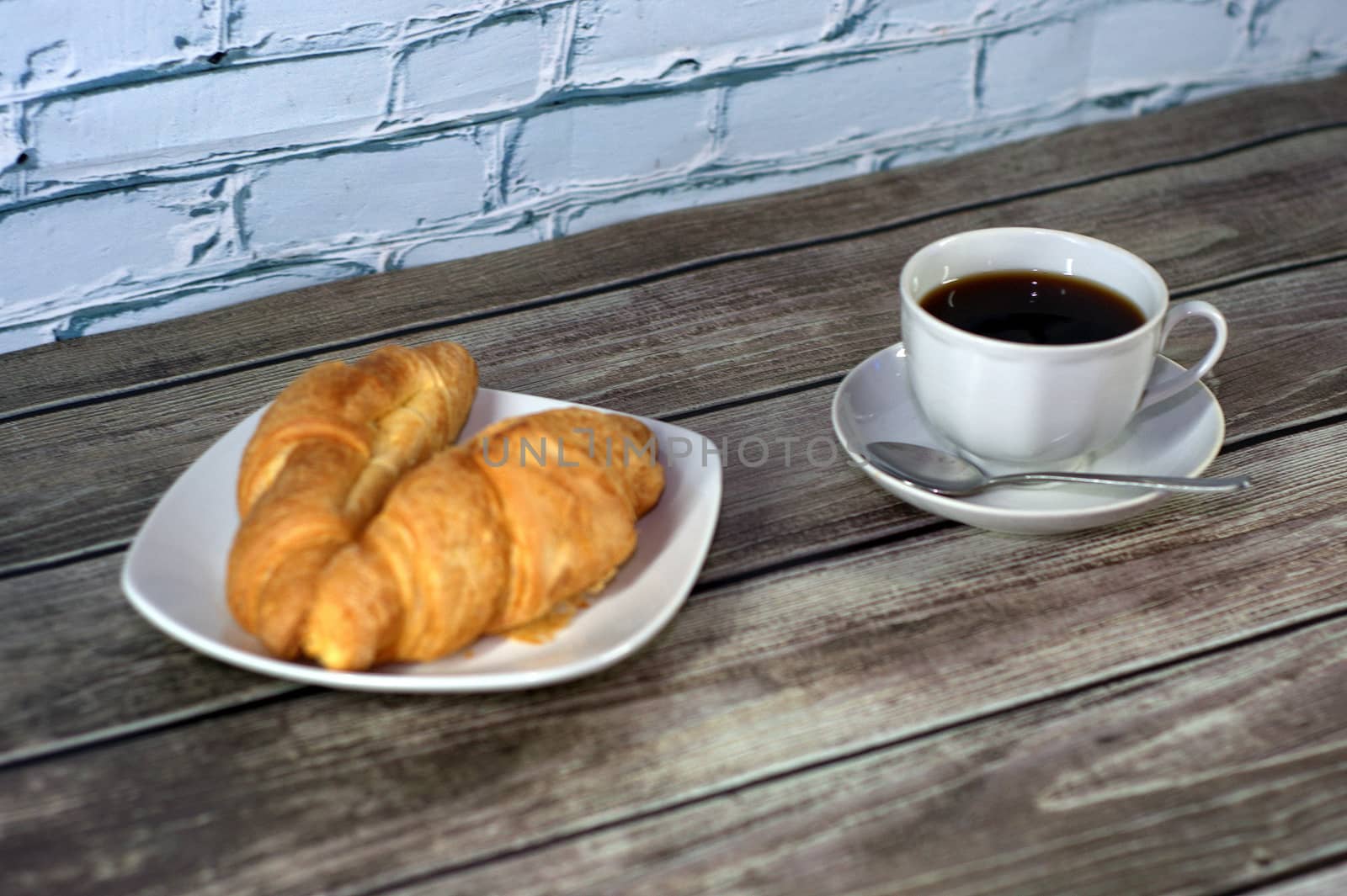 Light breakfast, a cup of black coffee with two croissants.