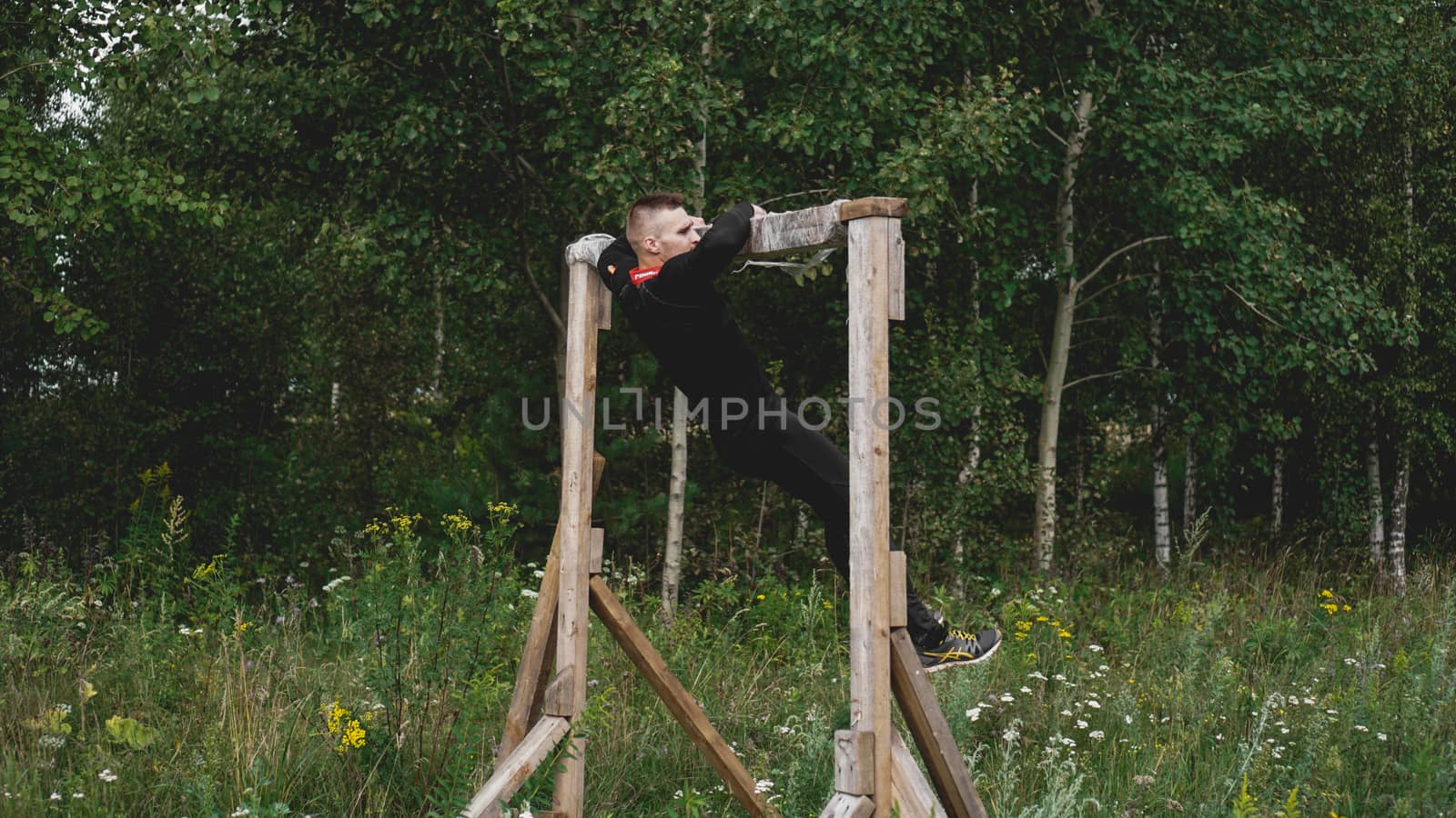 Man passing through hurdles during obstacle course in boot or sport competition