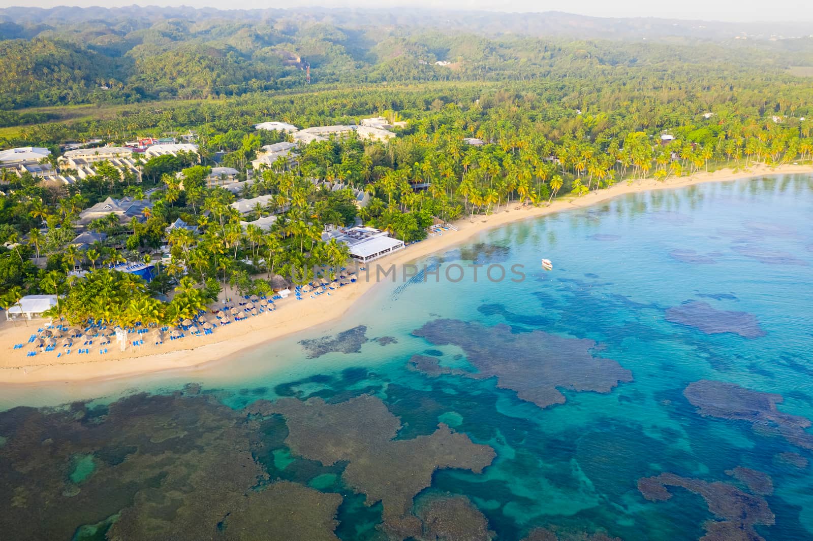 Drone shot of tropical beach with white boat anchored.Samana peninsula,Bahia Principe beach,Dominican Republic.