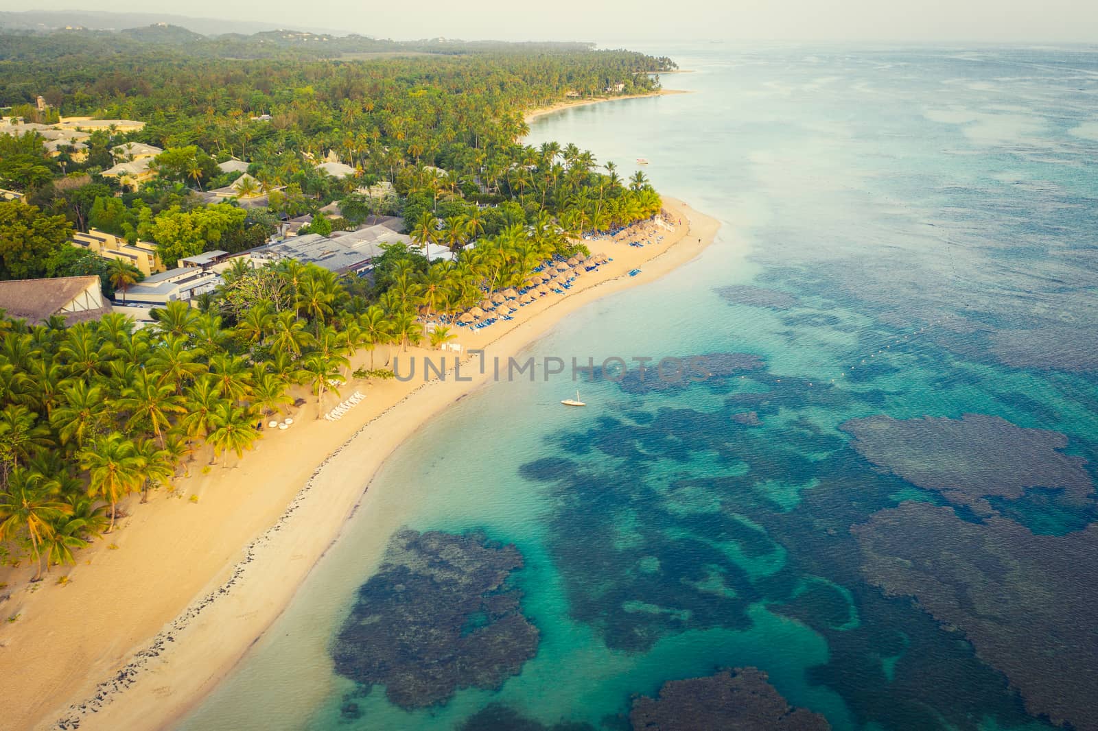 Drone shot of tropical beach with white boat anchored.Samana peninsula,Bahia Principe beach,Dominican Republic.