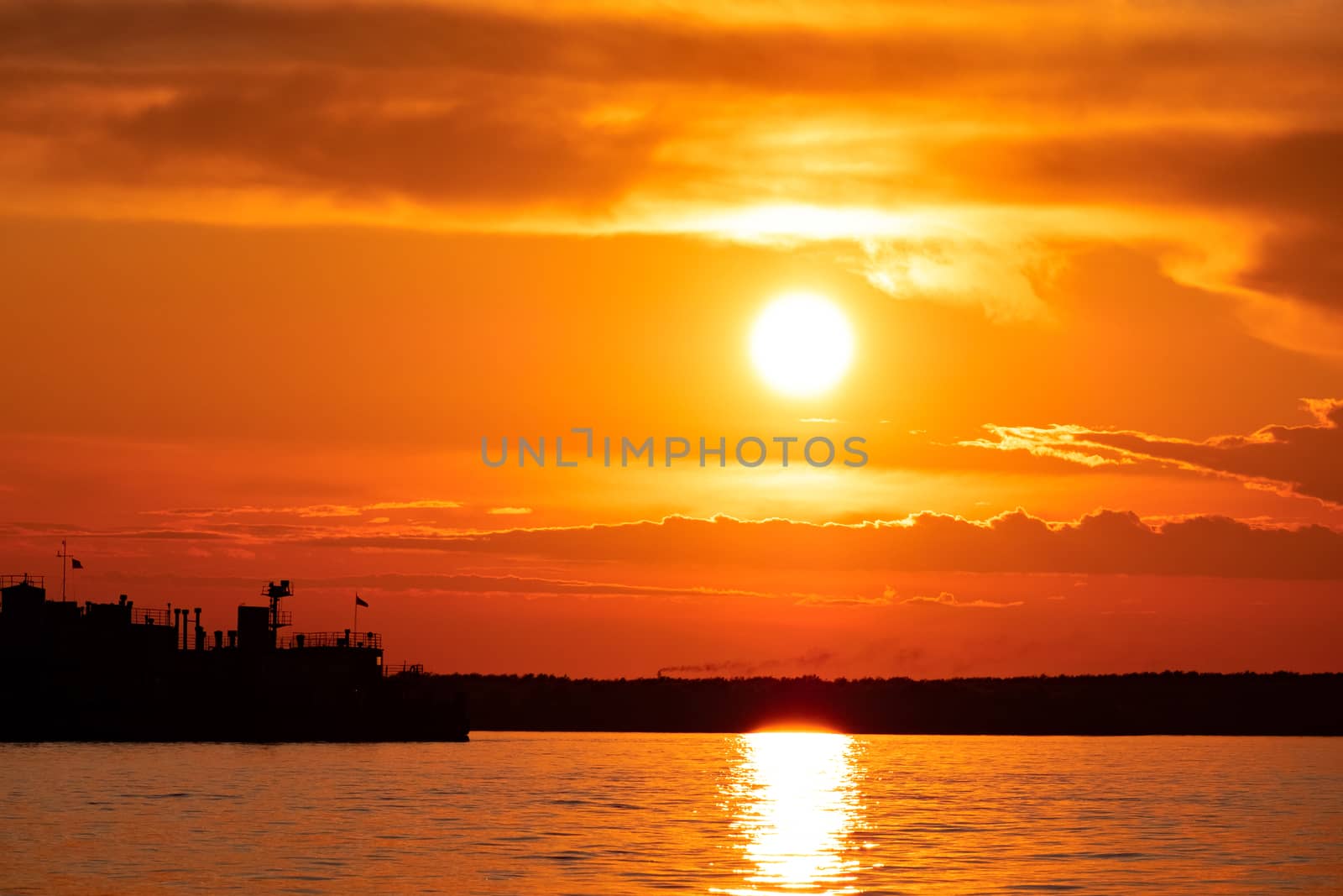 Sunset on the embankment of the Amur river in Khabarovsk. The sun set over the horizon. The embankment is lit by lanterns.