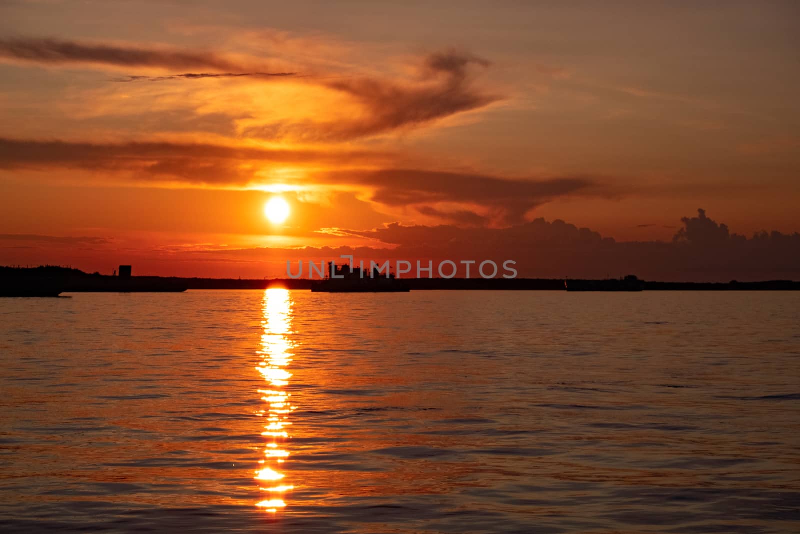 Sunset on the embankment of the Amur river in Khabarovsk. The sun set over the horizon. The embankment is lit by lanterns.