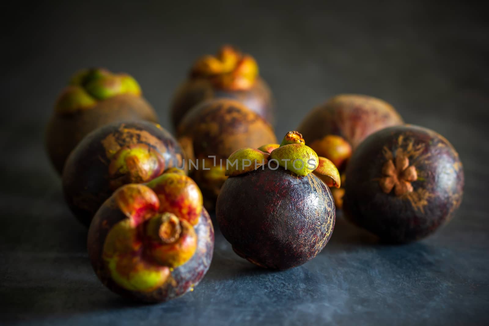 Mangosteen on black cement floor and morning light. Is a seasonal fruit in Thailand. Closeup and copy space for text.