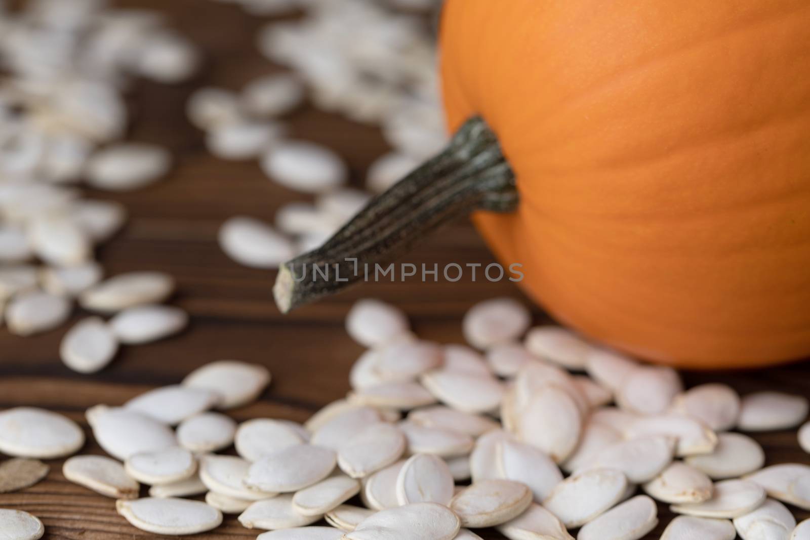 Fresh orange pumpkin and pimpkin seeds close-up on wooden background