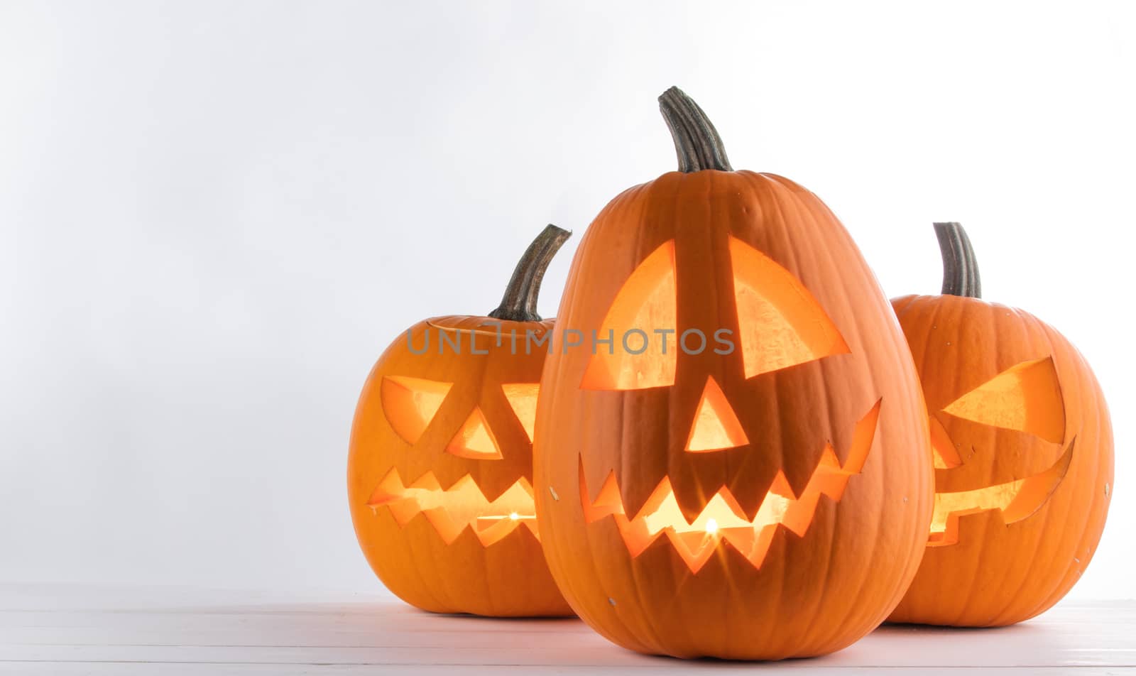 Three glowing Halloween Pumpkins on white background
