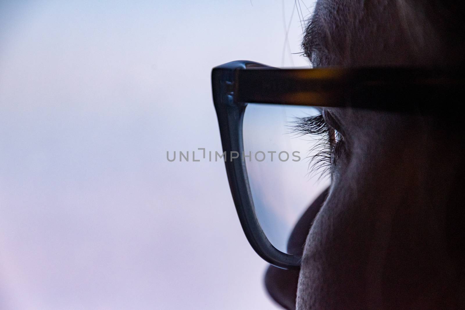 Close up of eye with glasses looking thoughtfully out of the window