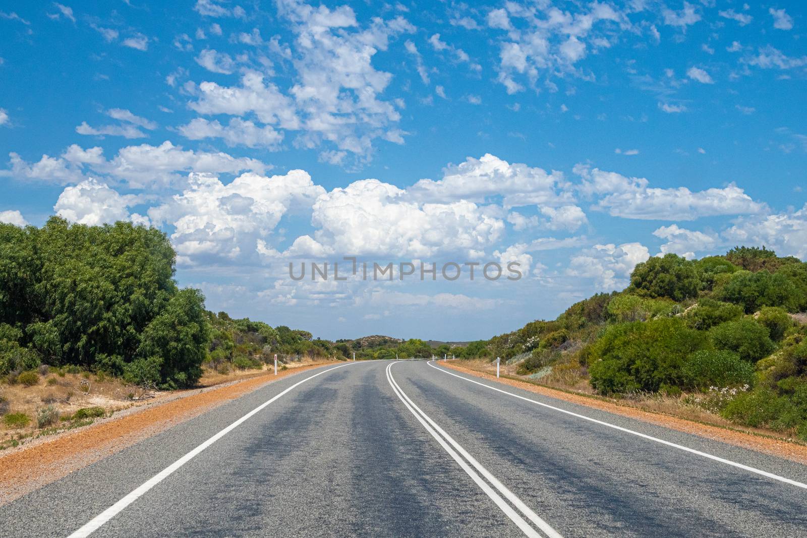 Empty road through green landscape in Australia storm clouds forming in sky