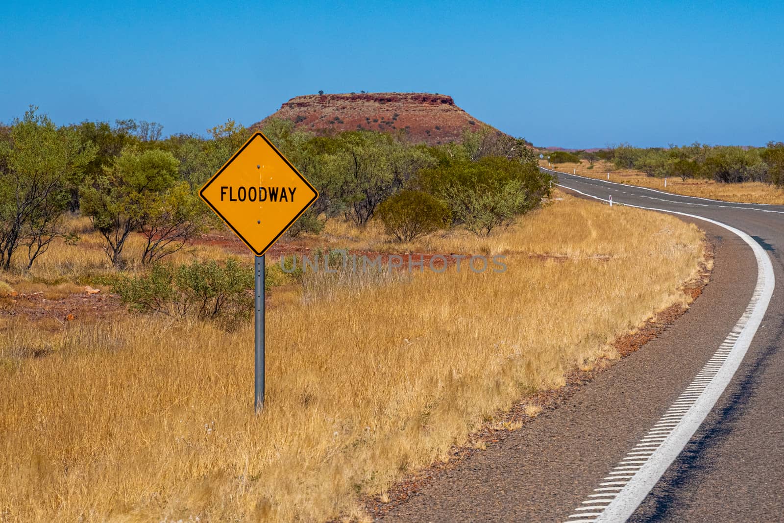Flood way street sign besides road in Australian bush by MXW_Stock