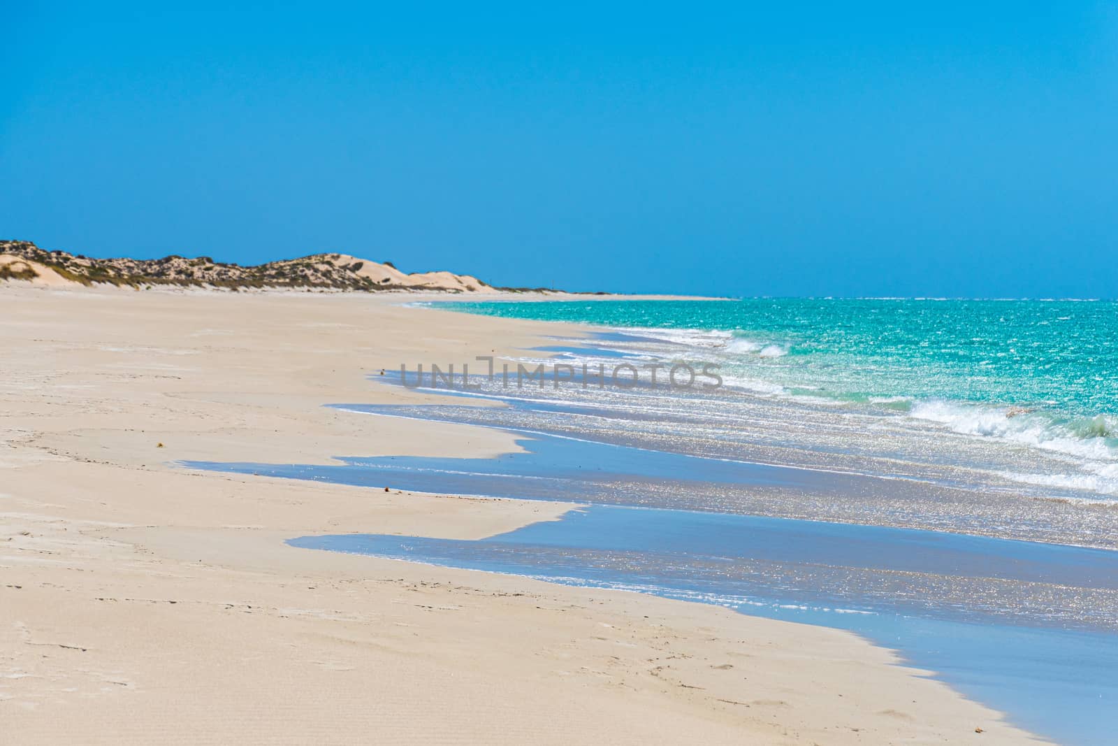 Long and empty beach of Coral Bay blue sky and turquoise water of Indian Ocean